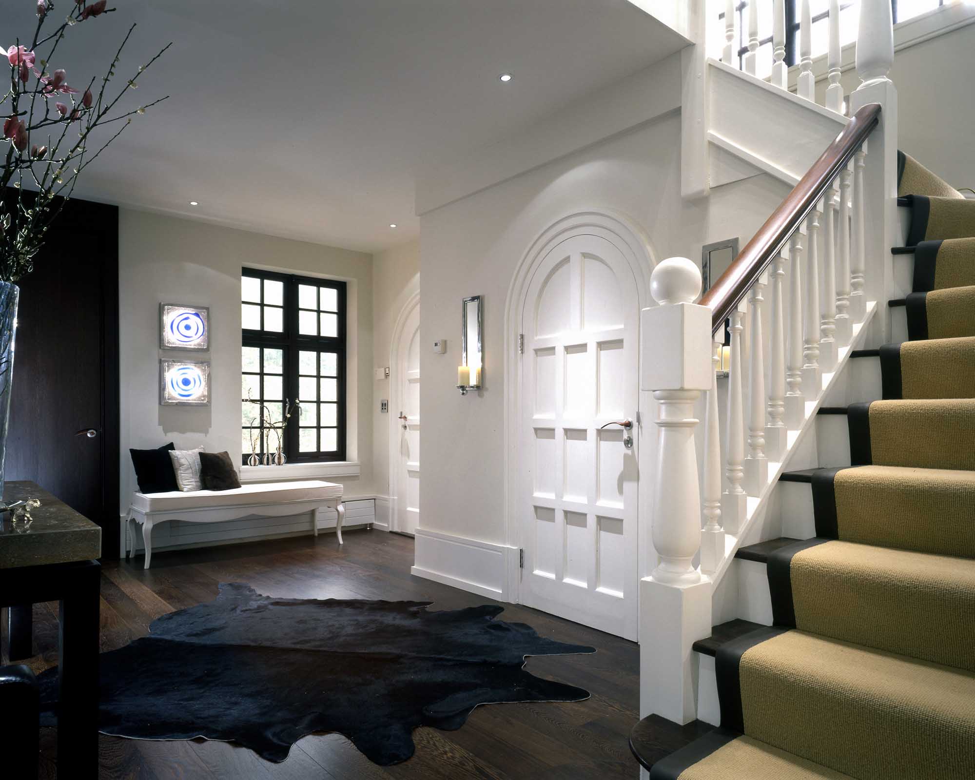 Contemporary, transitional entryway foyer with arched doorway, stairs, animal pelt rug.