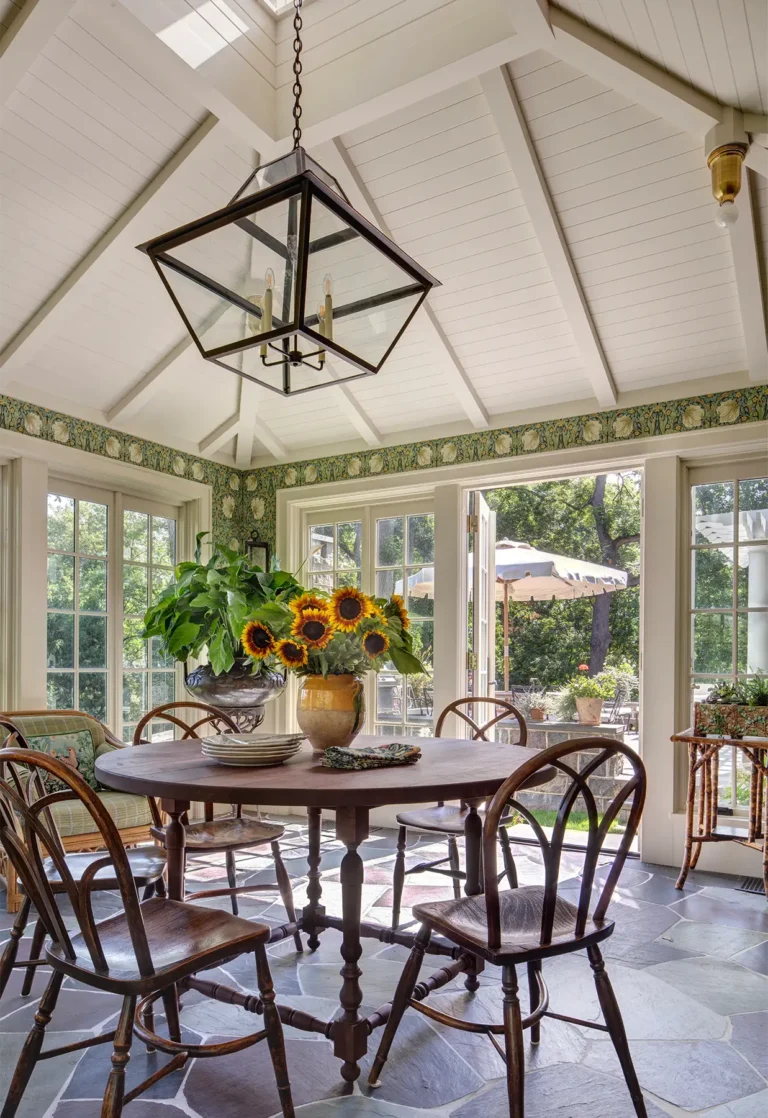 Dining nook with round wooden table, sunflowers centerpiece, and French doors to patio
