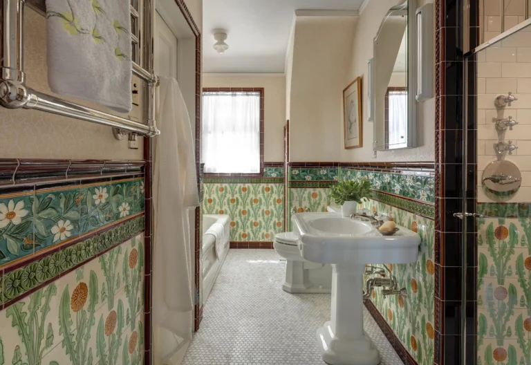 Bathroom with decorative floral tile wainscoting, pedestal sink, and vintage fixtures