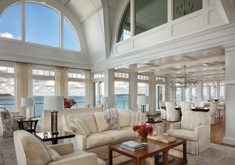 Living room with double-height windows overlooking the bay in a Huntington Bay waterfront home.