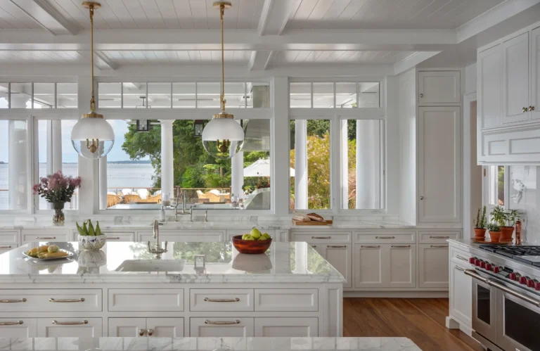 White kitchen with marble island and brass pendant lighting in a Huntington Bay waterfront home.