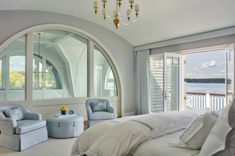 Primary bedroom with arched window and balcony overlooking Huntington Bay waterfront.