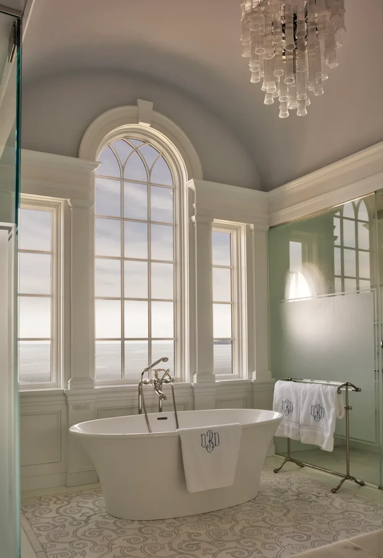 Arched window above freestanding tub overlooking the bay in a Huntington Bay waterfront home.