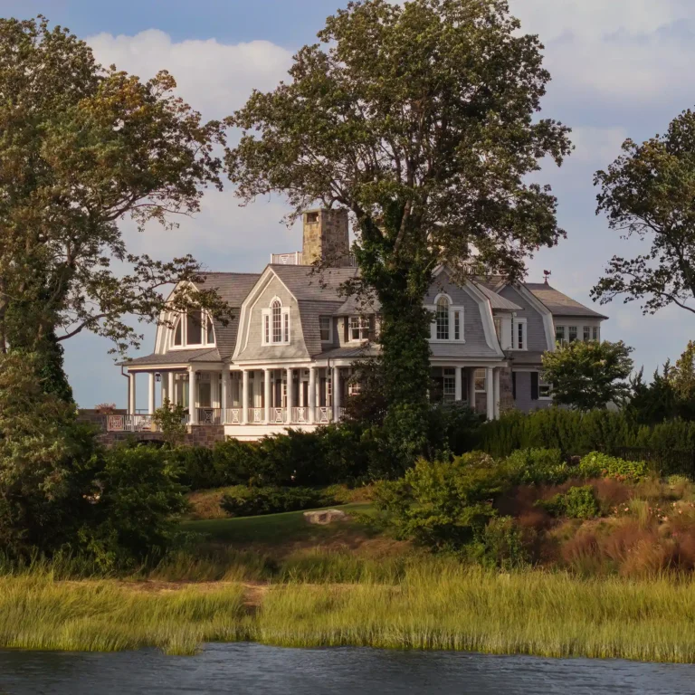 Huntington Bay waterfront home framed by mature trees, with Shingle Style architecture overlooking the shoreline.