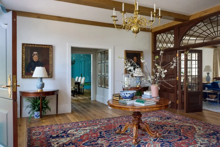 Cape Dutch entry hall with mahogany screen, brass chandelier, patterned rug, and views into adjoining rooms