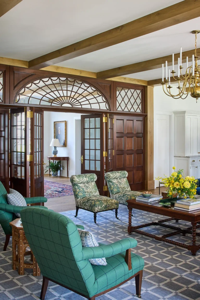 Living room in a Cape Dutch residence with mahogany screen, arched transom, patterned rug, chandelier, and view toward the entry hall