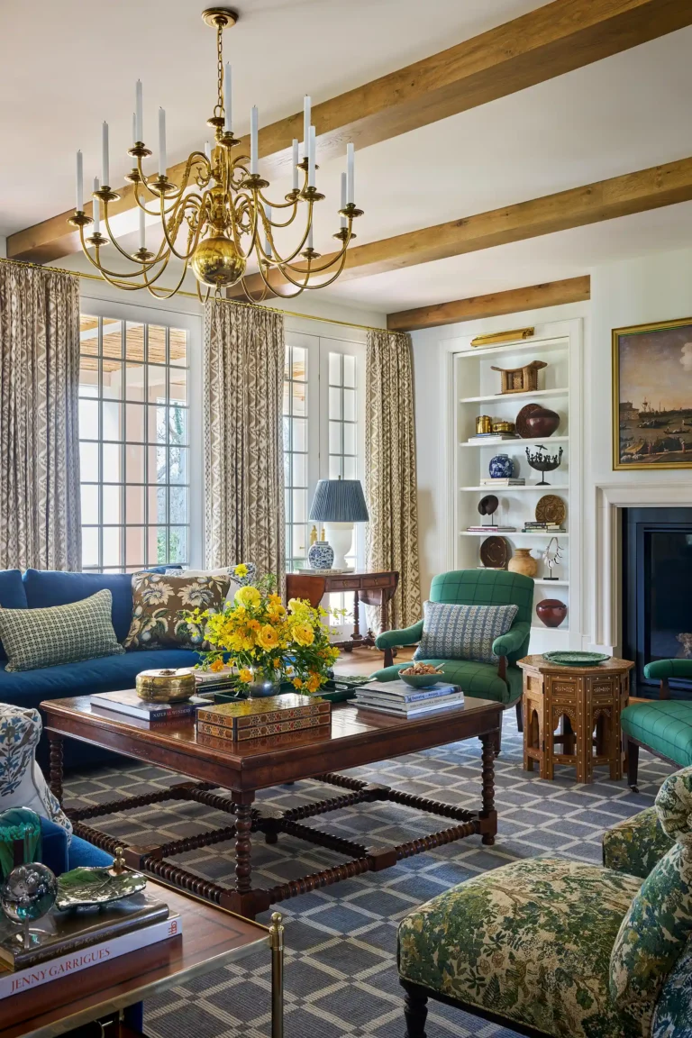 Cape Dutch living room with blue sofa, green armchairs, brass chandelier, built-in shelves, and tall windows