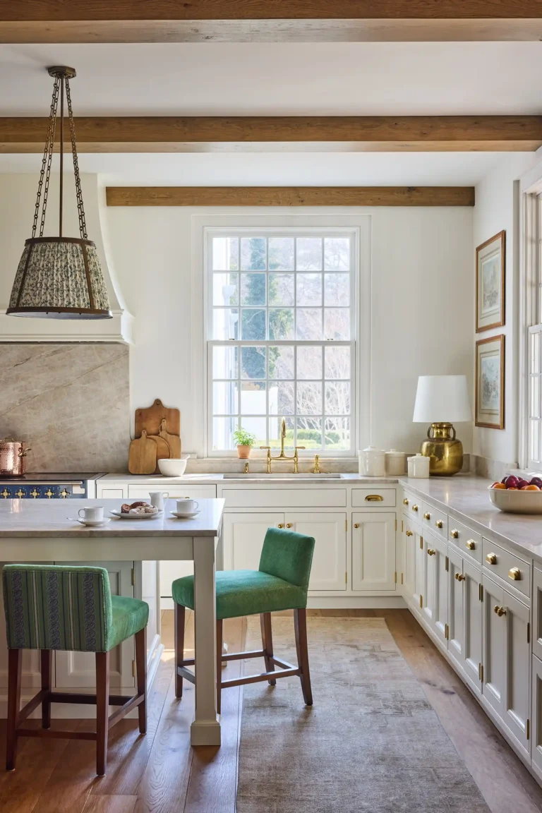 White kitchen in Cape Dutch home with exposed beams, pendant lights, island seating, and wide-plank oak flooring