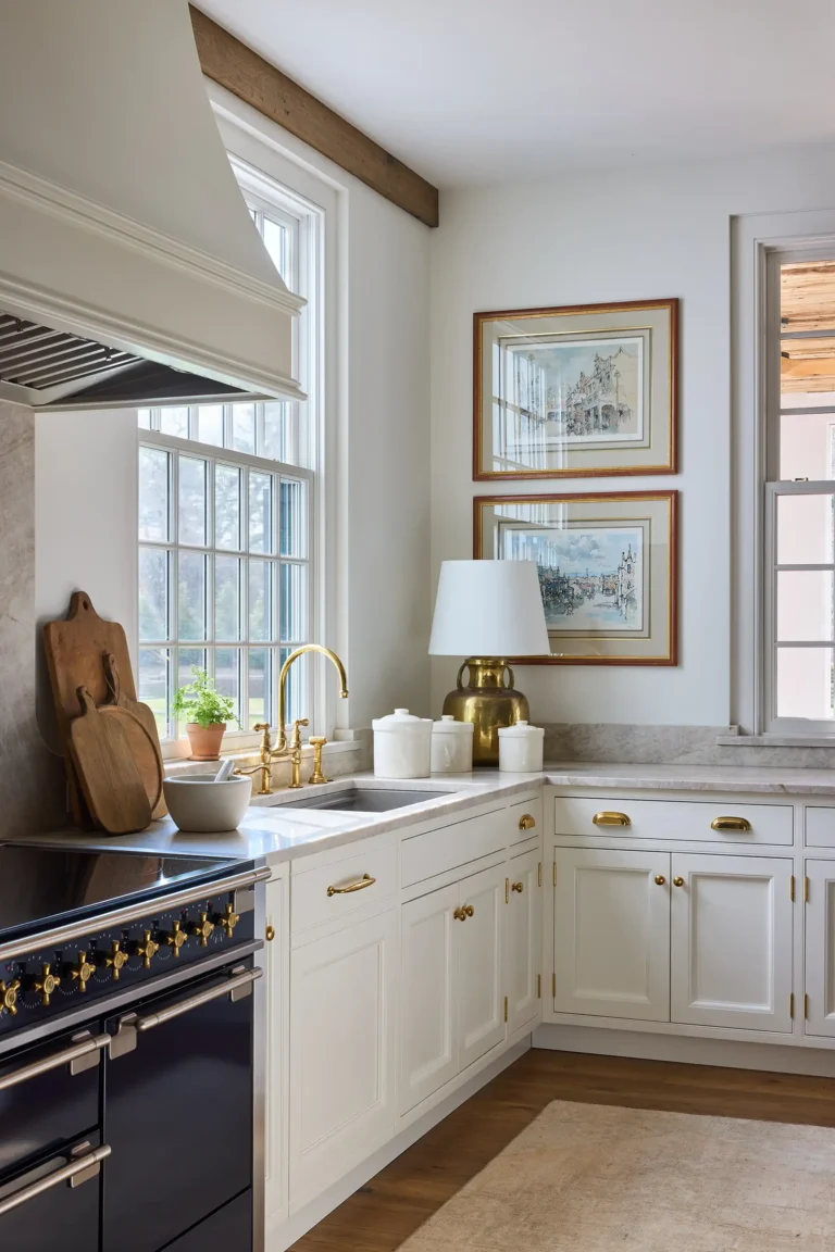 Cape Dutch kitchen detail with white range hood, black range, window light, stone counters, and custom cabinetry