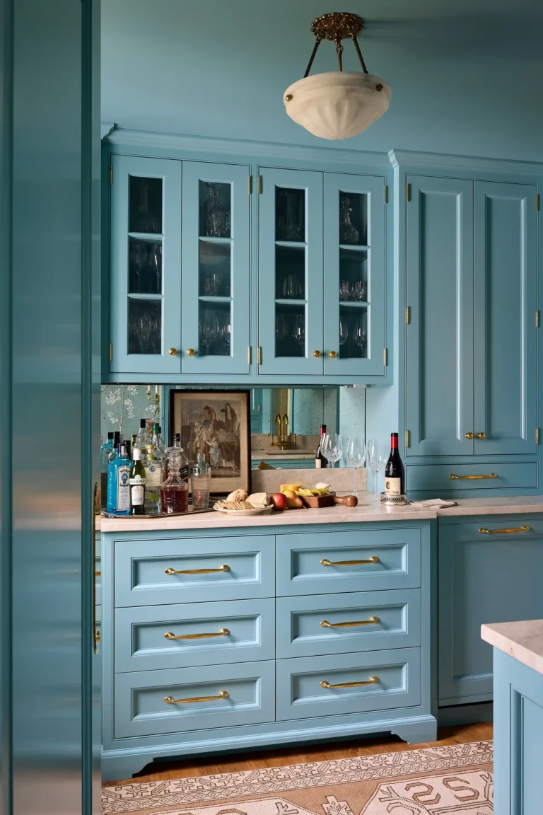 Blue butler’s pantry with glass-front cabinets, stone countertop, brass hardware, and sink in Cape Dutch residence