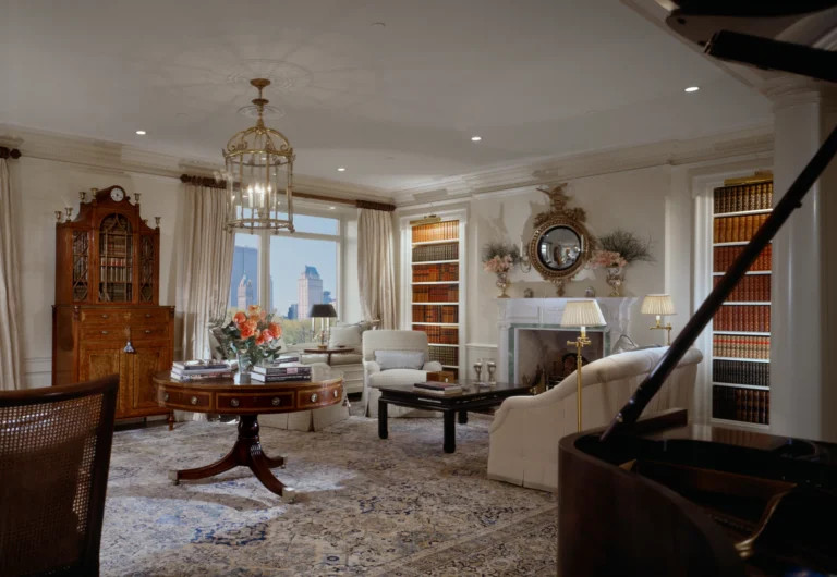 Formal living room in a luxury Manhattan apartment renovation with grand piano, marble fireplace, built-in bookcases, brass lantern chandelier, classical trim, and Central Park views.